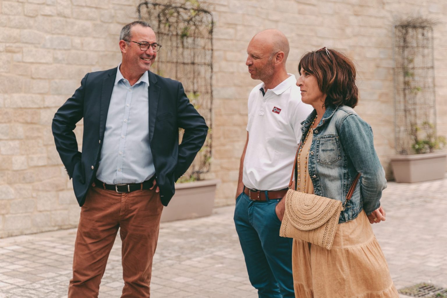 Photographie d'entreprise sur laquelle on voit trois personnes entrain de discuter en extérieur avant une réunion