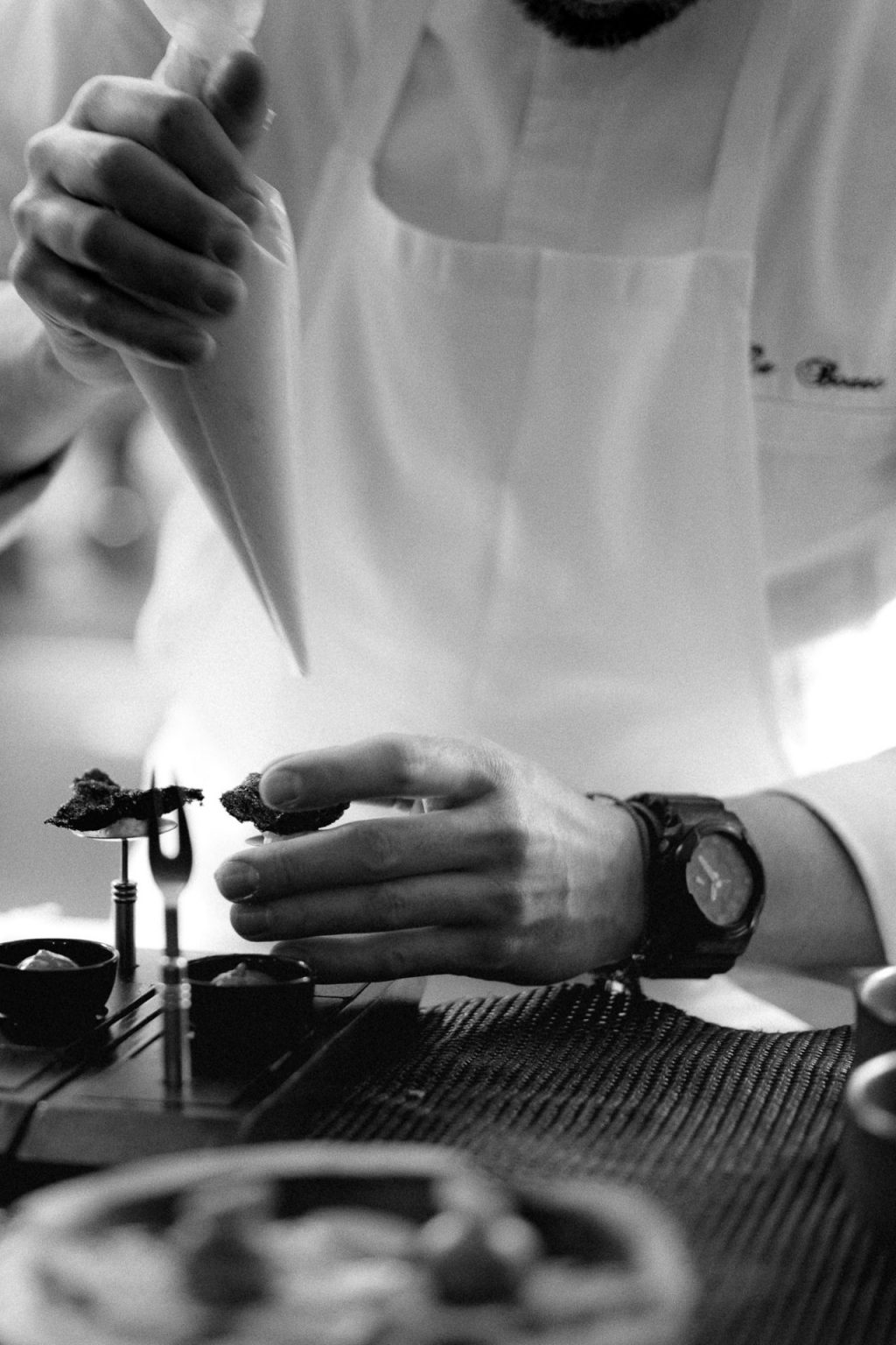 Photographie en noir et blanc d'un cuisiner entrain de dresser un plat