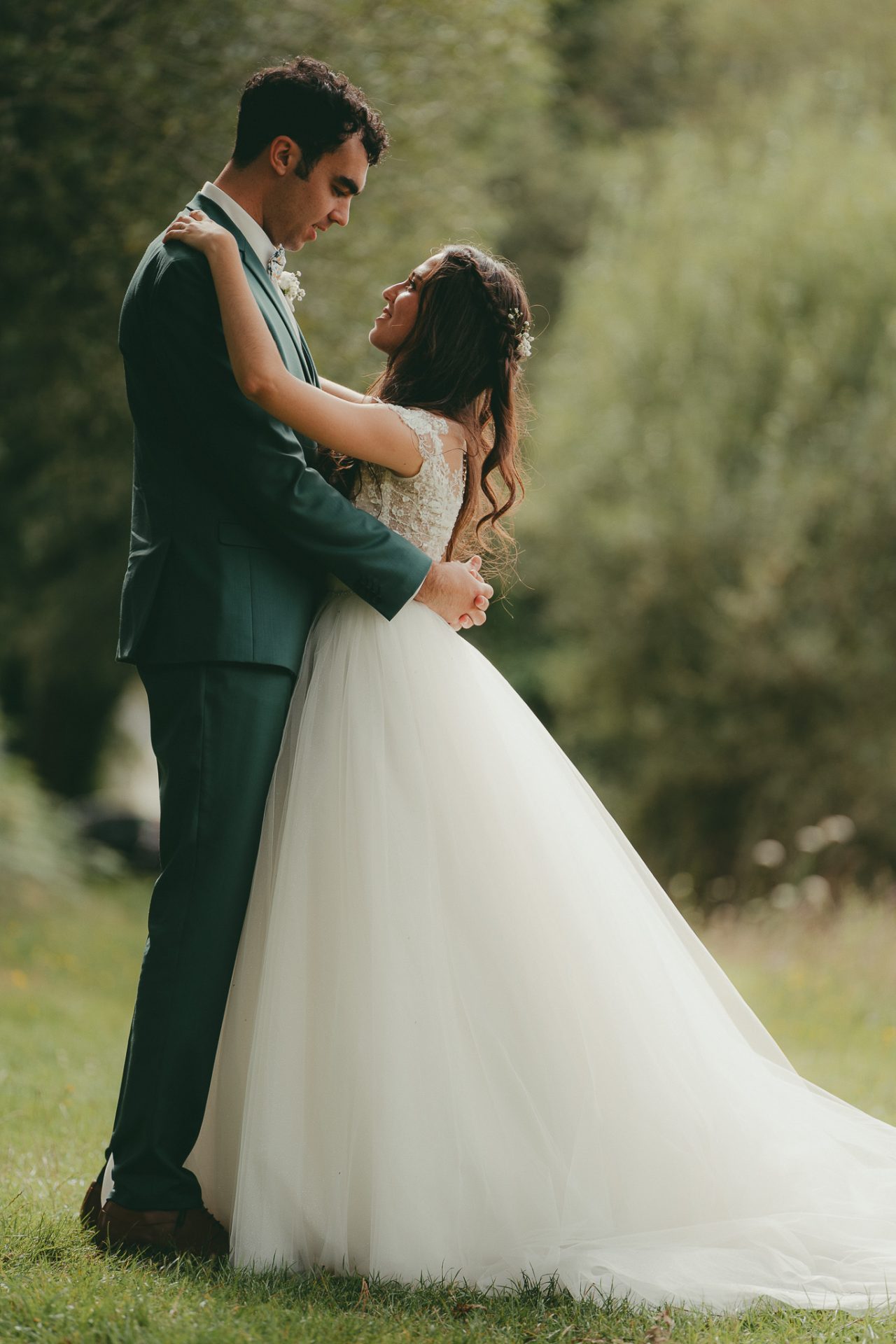 Photographie d'une jeune mariée en robe blanche dans les bras de son époux dans la campagne Bretonne