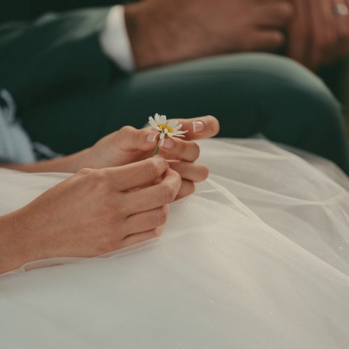 Photographie de mariage d'un jeune femme tenant une fleur dans sa main