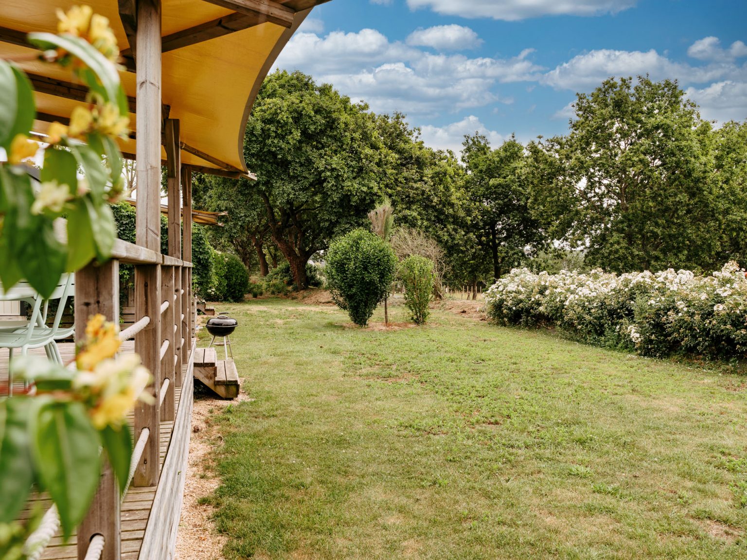 Photographie de la terrasse d'un mobil-home donnant sur un espace paysager dans un camping en Bretagne