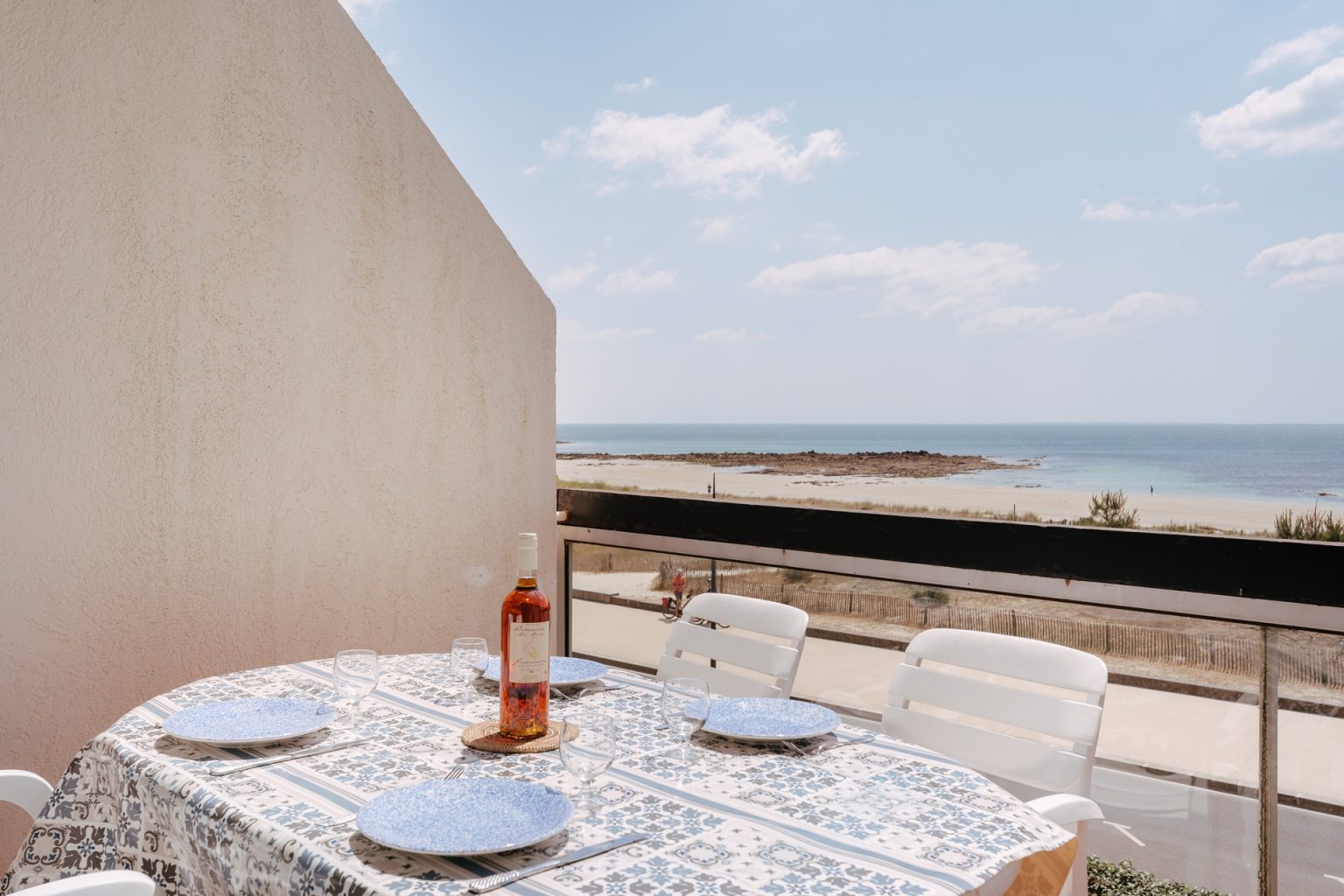 Photographie d'une table dressée sur la terrasse d'un appartement avec vue sur la grande plage de Carnac