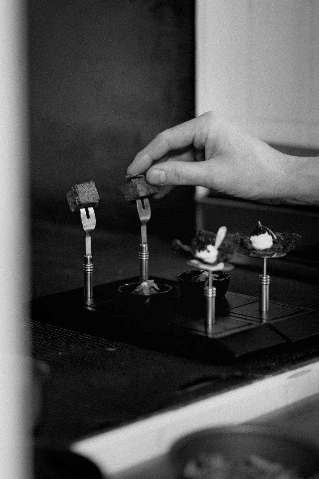 Photographie en noir et blanc d'un cuisinier dressant une assiette